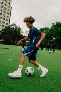 A young player in a Brasil Jordan kit dribbling through cones during the training session