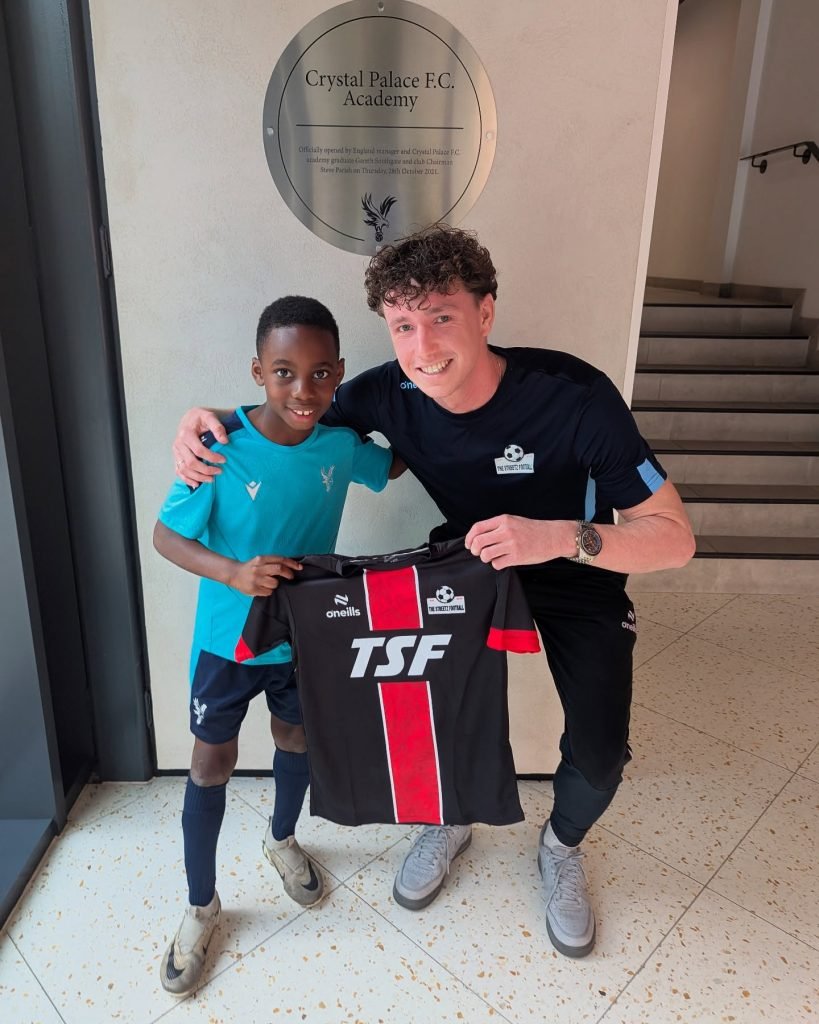 Coach Dom holding a TSF kit with a young player at the Crystal Palace FC Academy