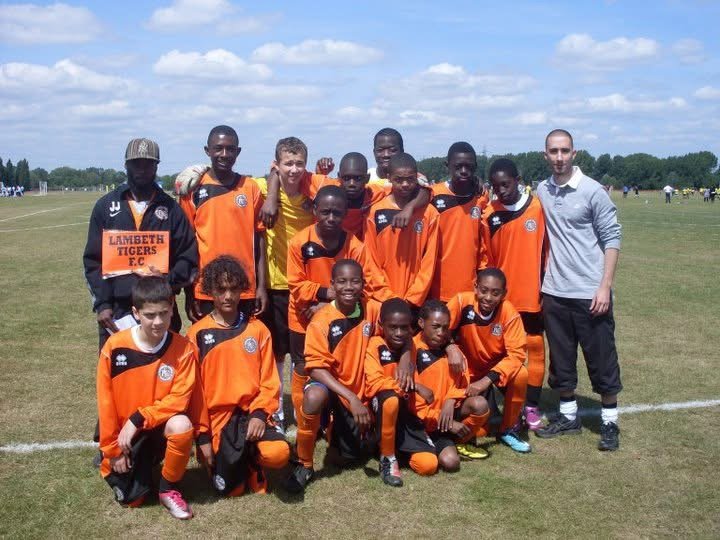 The original Lambeth Tigers youth team posed together on a grass pitch