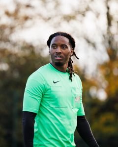 A London FA match official in a green referee shirt on the touchline