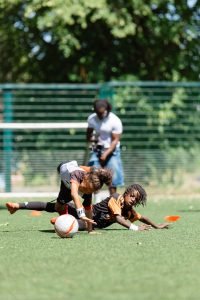Two under-9 players hitting the deck as they battle for the ball in a 1v1 duel